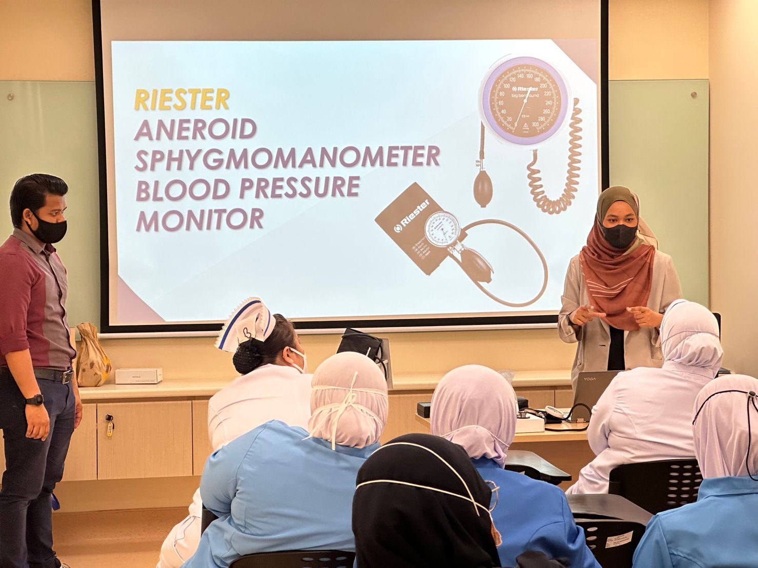 Teepham staff training clinic nurses on a Riester blood pressure monitor, with a product slide on screen